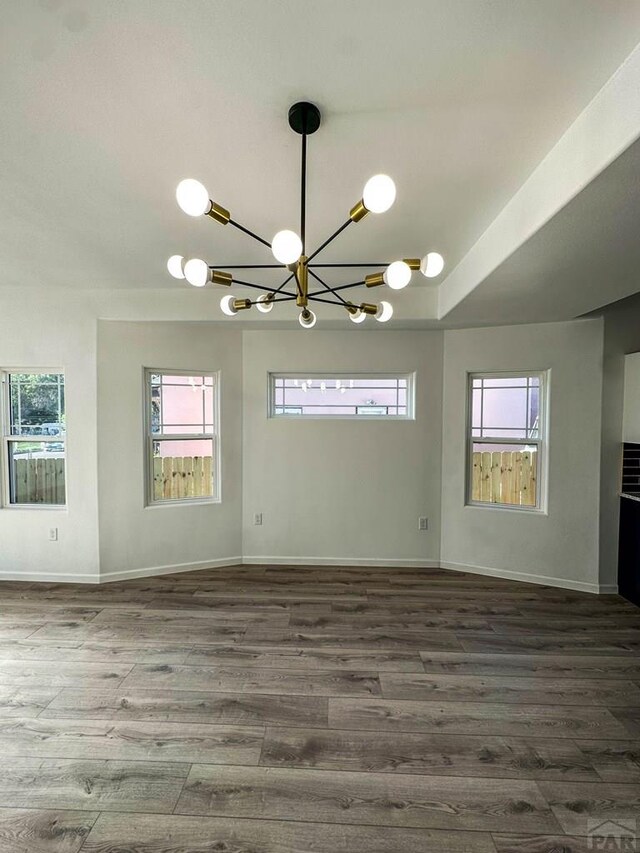 spare room featuring baseboards, dark wood-style flooring, and a wealth of natural light