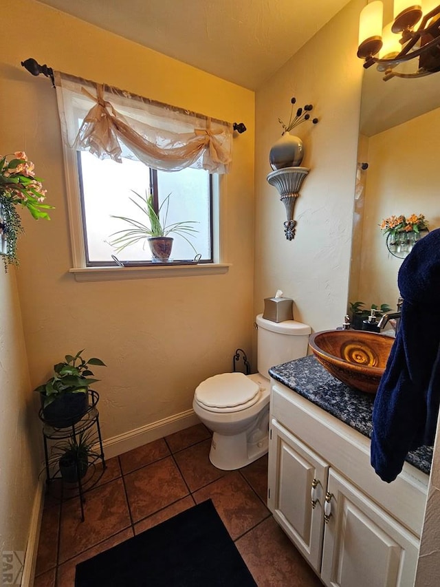 half bathroom featuring tile patterned floors, baseboards, toilet, and vanity