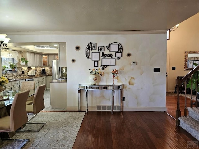 dining space featuring a notable chandelier, stairway, crown molding, and wood finished floors