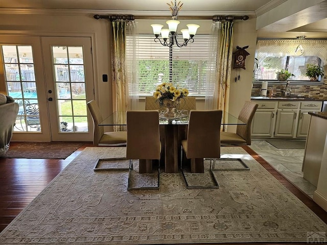 dining space featuring an inviting chandelier, wood finished floors, french doors, and ornamental molding