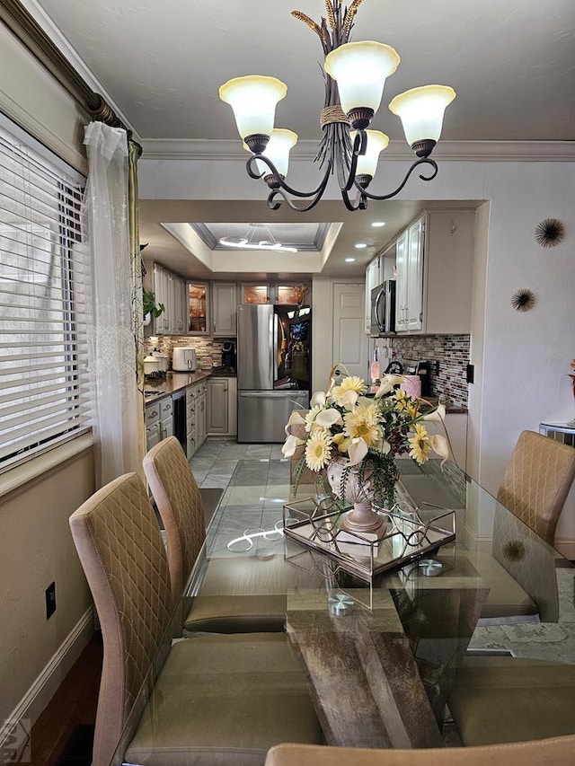 dining room with a notable chandelier, baseboards, crown molding, and a tray ceiling