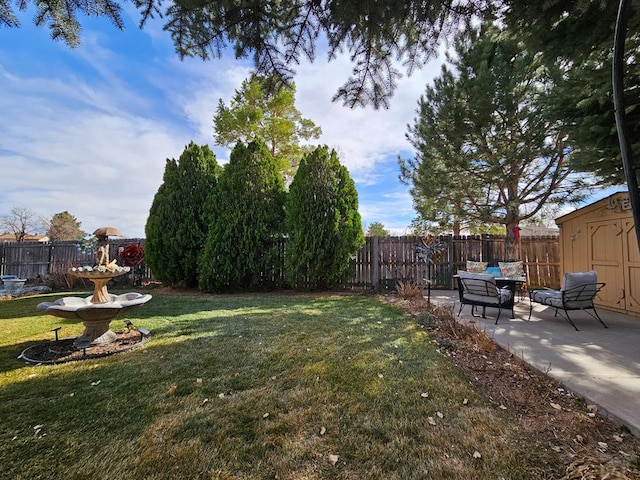 view of yard featuring a storage unit, an outbuilding, a fenced backyard, and a patio area