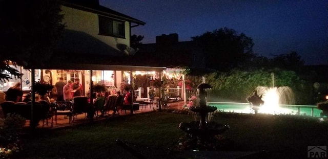 pool at night featuring a patio