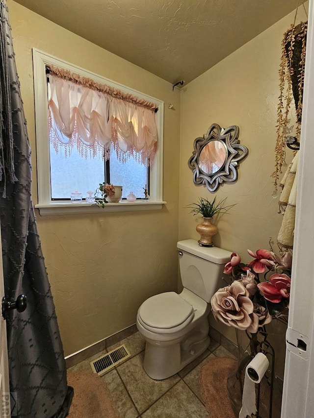 bathroom featuring baseboards, visible vents, tile patterned flooring, a textured ceiling, and toilet