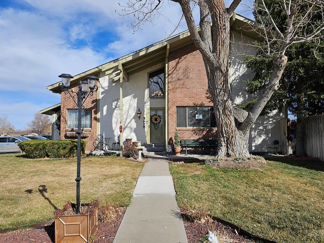 view of front of home with a front yard, fence, and brick siding