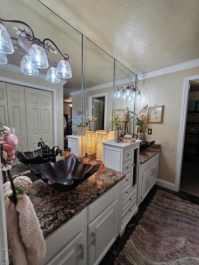 kitchen featuring white cabinetry, crown molding, baseboards, and a sink