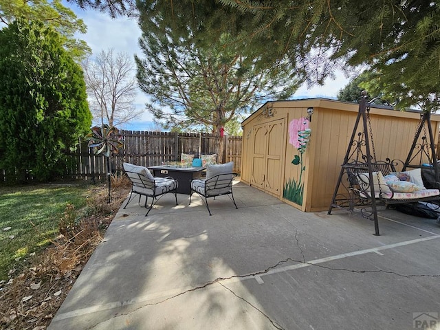 view of patio with a storage shed, fence, an outbuilding, and a fire pit