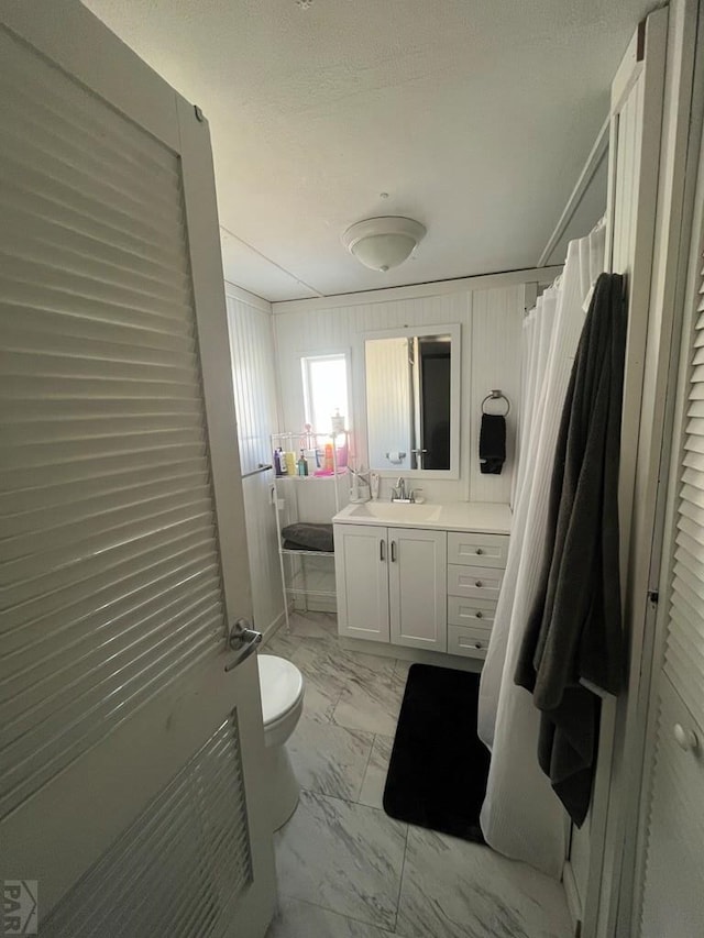 bathroom with toilet, marble finish floor, a shower with curtain, and vanity