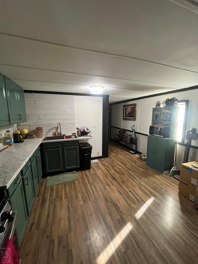 interior space with range, wood finished floors, light countertops, green cabinets, and a sink