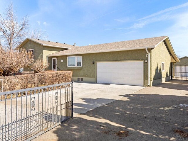 single story home featuring driveway, a shingled roof, an attached garage, fence, and stucco siding