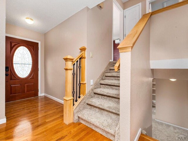 entrance foyer with stairway, wood finished floors, and baseboards