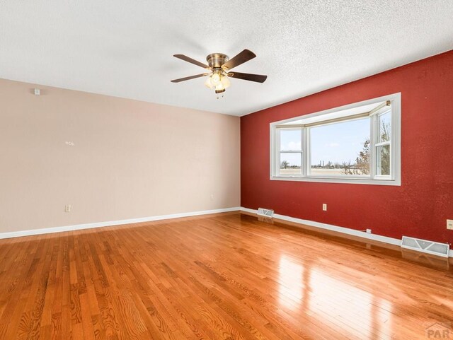 empty room featuring light wood-style flooring, visible vents, and baseboards