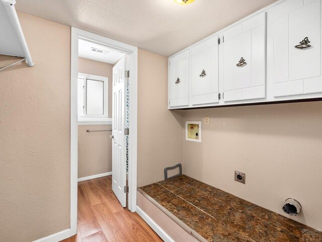 washroom featuring hookup for a washing machine, baseboards, cabinet space, light wood finished floors, and electric dryer hookup