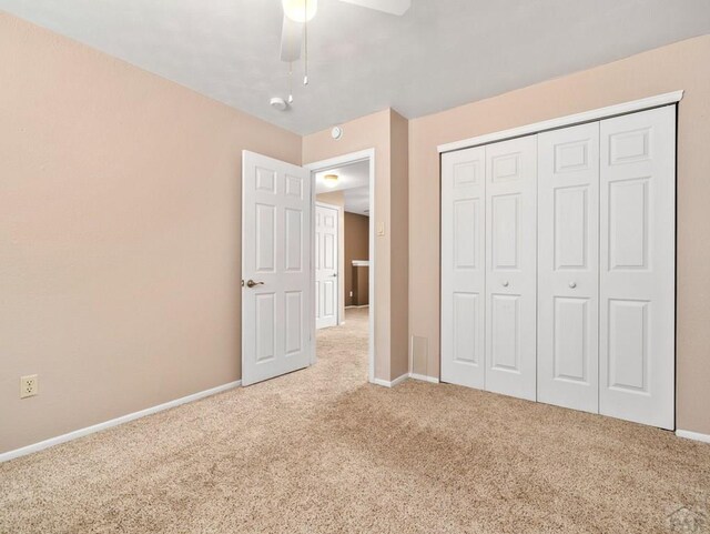 unfurnished bedroom with carpet floors, a ceiling fan, baseboards, and a closet