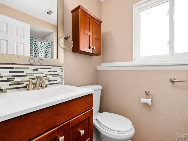 full bathroom with toilet, tasteful backsplash, vanity, and visible vents