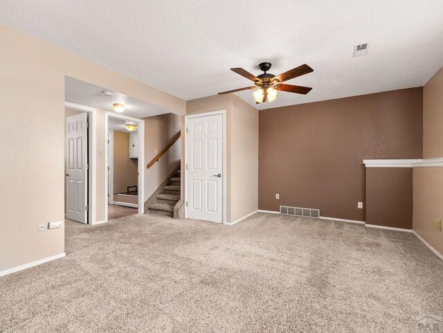 empty room featuring baseboards, visible vents, carpet, stairs, and a textured ceiling