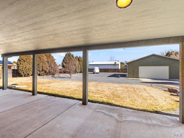 view of patio featuring an outdoor structure, a detached garage, and fence