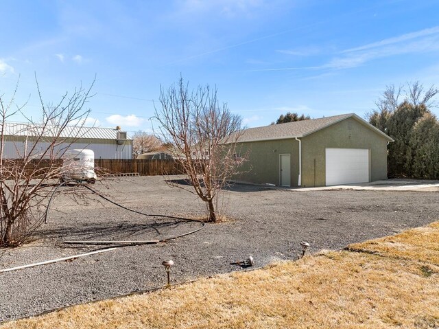 view of property exterior with a garage, fence, and stucco siding