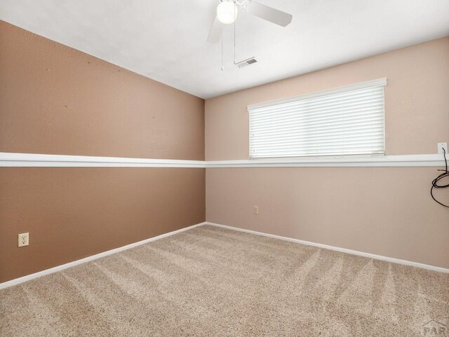 carpeted empty room with ceiling fan, visible vents, and baseboards