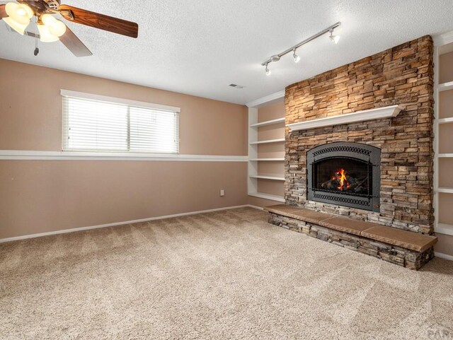 unfurnished living room featuring a textured ceiling, a fireplace, carpet flooring, and built in features