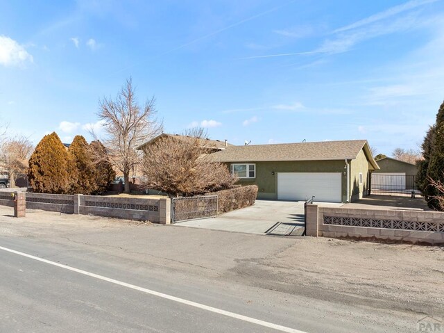 ranch-style house featuring a garage, a fenced front yard, concrete driveway, and stucco siding