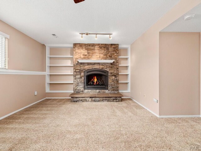 unfurnished living room featuring a textured ceiling, built in shelves, carpet flooring, and baseboards