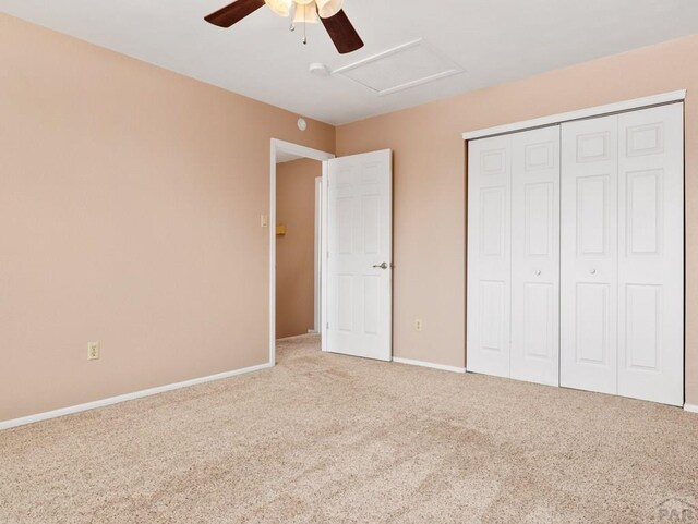 unfurnished bedroom featuring ceiling fan, carpet floors, baseboards, a closet, and attic access