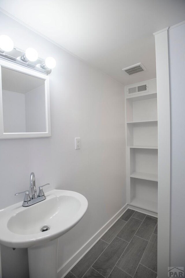 bathroom with baseboards, visible vents, and a sink