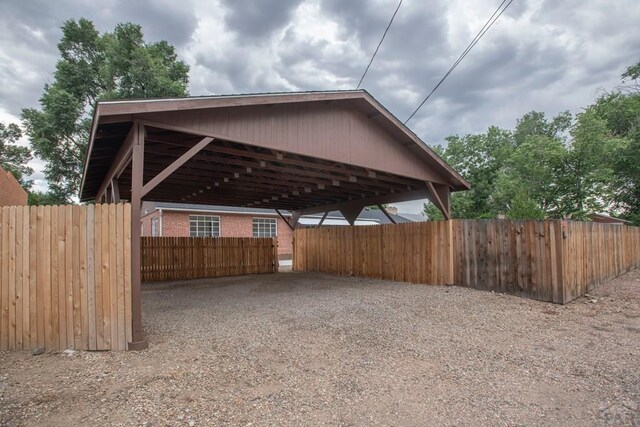 exterior space featuring a carport, gravel driveway, and fence