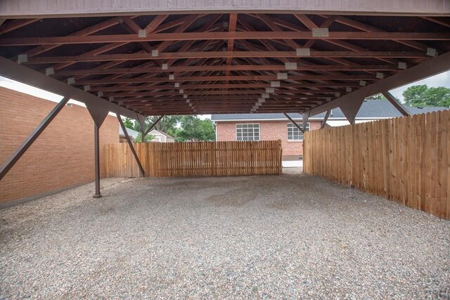 view of parking with fence and a carport