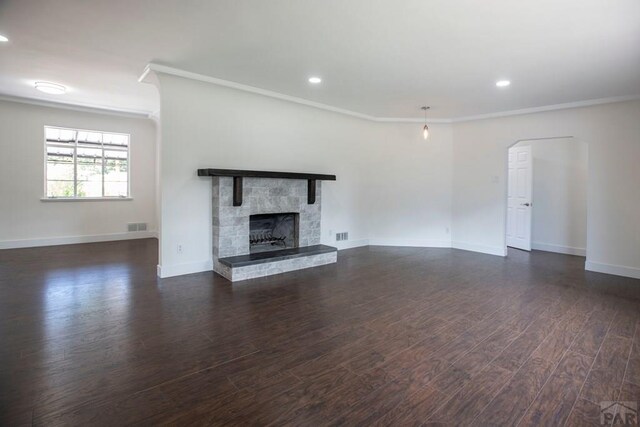 unfurnished living room featuring baseboards, dark wood finished floors, crown molding, a fireplace, and recessed lighting