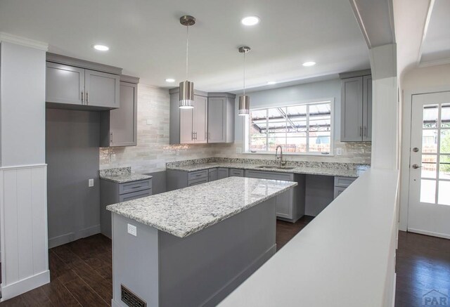 kitchen featuring a center island, pendant lighting, dark wood finished floors, visible vents, and a sink