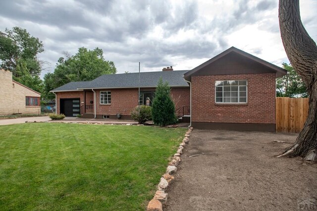 view of front of home featuring brick siding, an attached garage, a front lawn, and fence