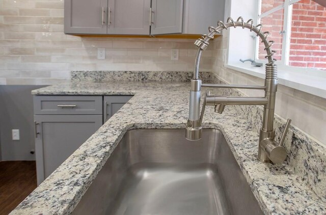 interior details featuring light stone counters, backsplash, and gray cabinets