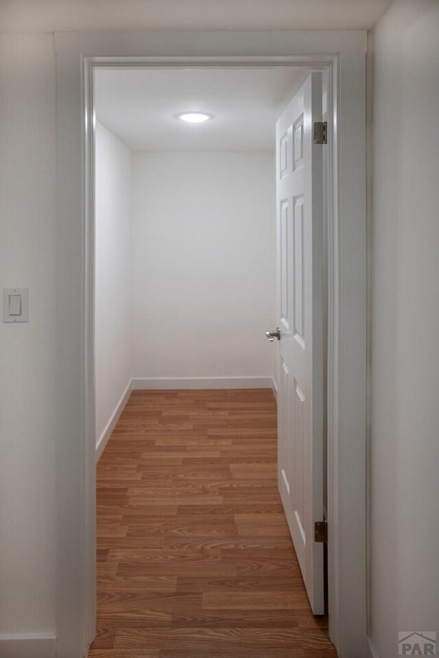 corridor featuring light wood-style floors and baseboards