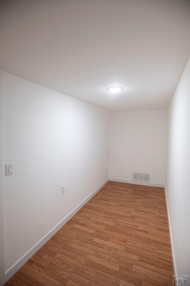 spare room featuring wood finished floors, visible vents, and baseboards