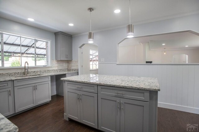 kitchen with light stone counters, gray cabinetry, a sink, dark wood-style floors, and pendant lighting