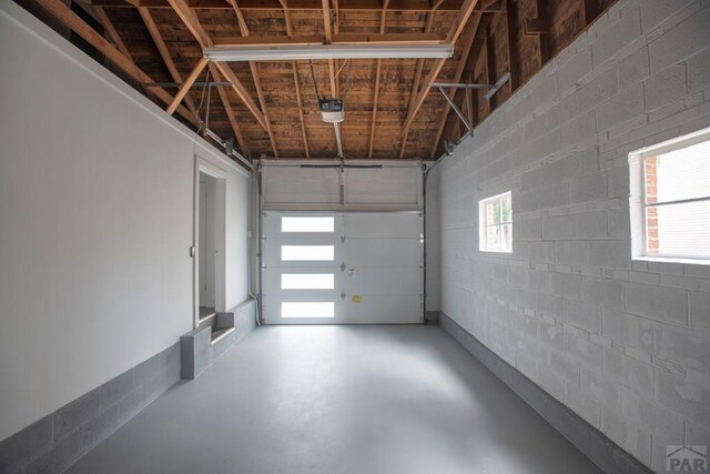 garage featuring concrete block wall and a garage door opener