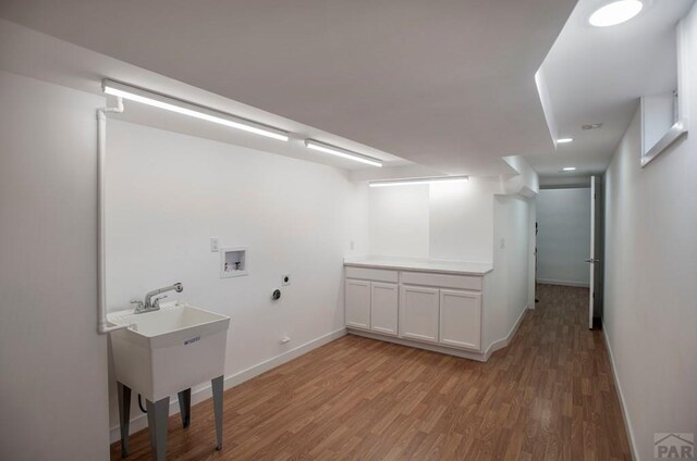 clothes washing area with hookup for a gas dryer, hookup for an electric dryer, washer hookup, baseboards, and light wood-type flooring