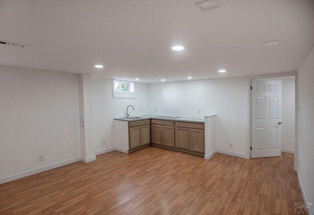 kitchen featuring light wood-style flooring, light countertops, a sink, and recessed lighting