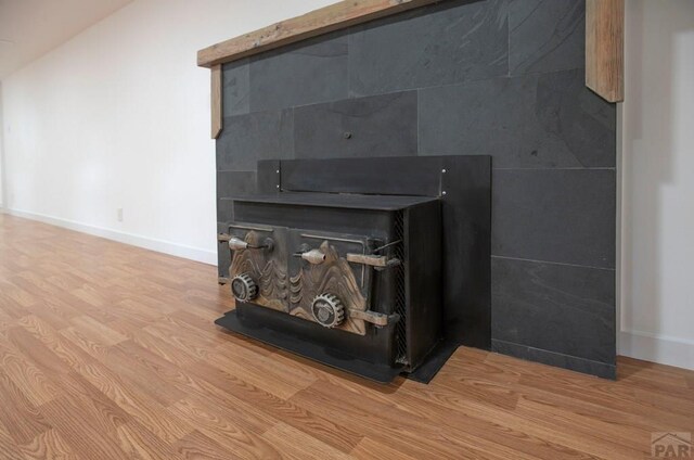 interior details with a wood stove, baseboards, and wood finished floors