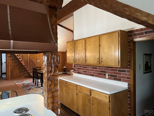 kitchen featuring brown cabinets, vaulted ceiling with beams, wooden walls, and light countertops