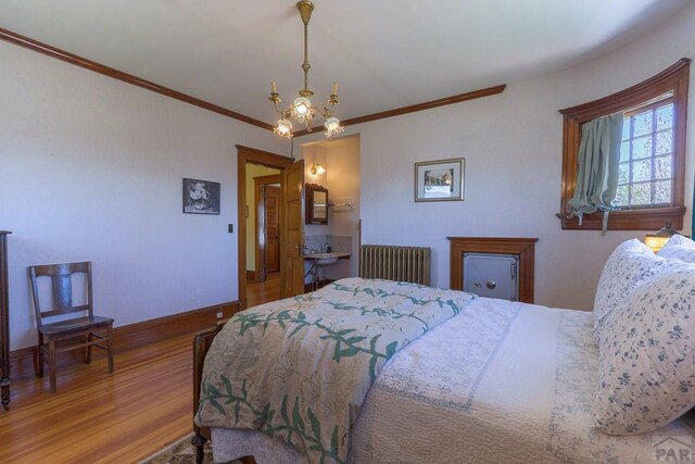 bedroom with baseboards, radiator heating unit, wood finished floors, crown molding, and a notable chandelier