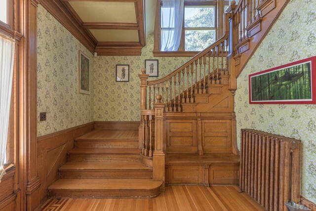 staircase featuring radiator, wainscoting, wood finished floors, and wallpapered walls