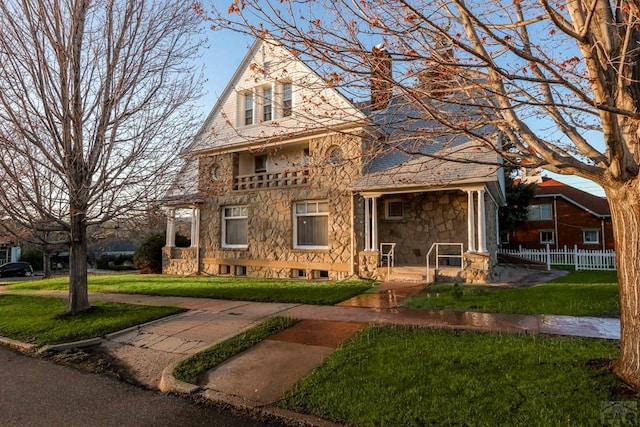 view of front of property featuring a front yard, stone siding, and fence