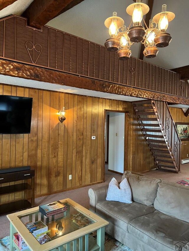 carpeted living room with a baseboard heating unit, wooden walls, stairway, and beamed ceiling