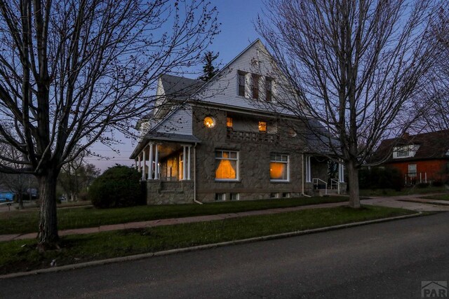 view of front of property with stone siding and a yard