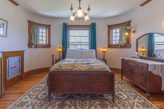 bedroom featuring a notable chandelier, baseboards, and wood finished floors