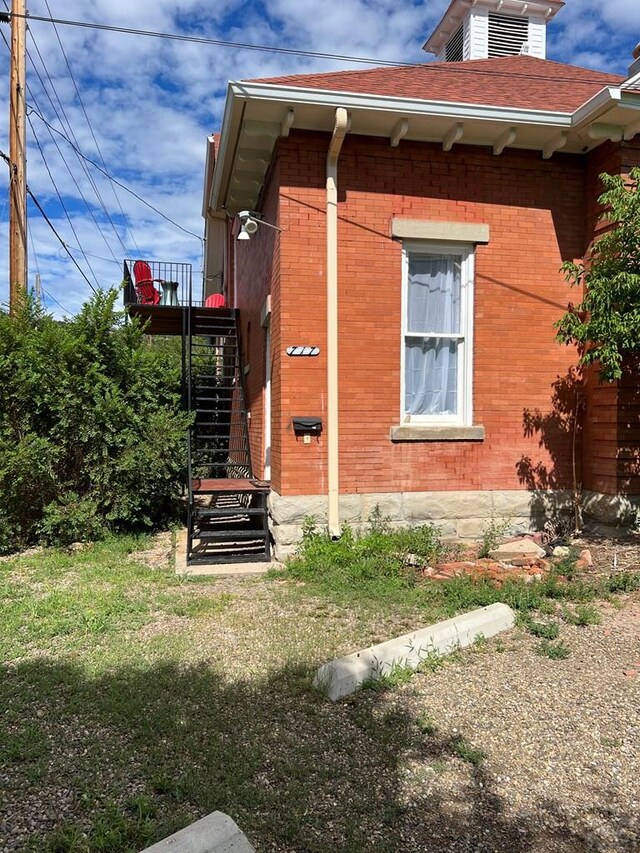 view of property exterior featuring a yard, stairs, and brick siding