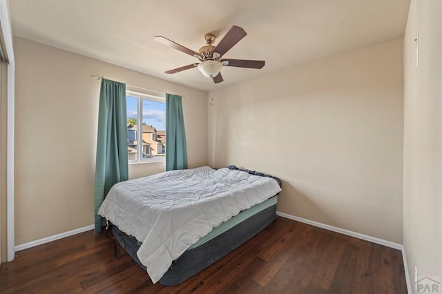 bedroom featuring baseboards, dark wood finished floors, and a ceiling fan